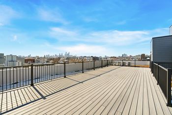 A wooden deck with a metal railing overlooking a city skyline